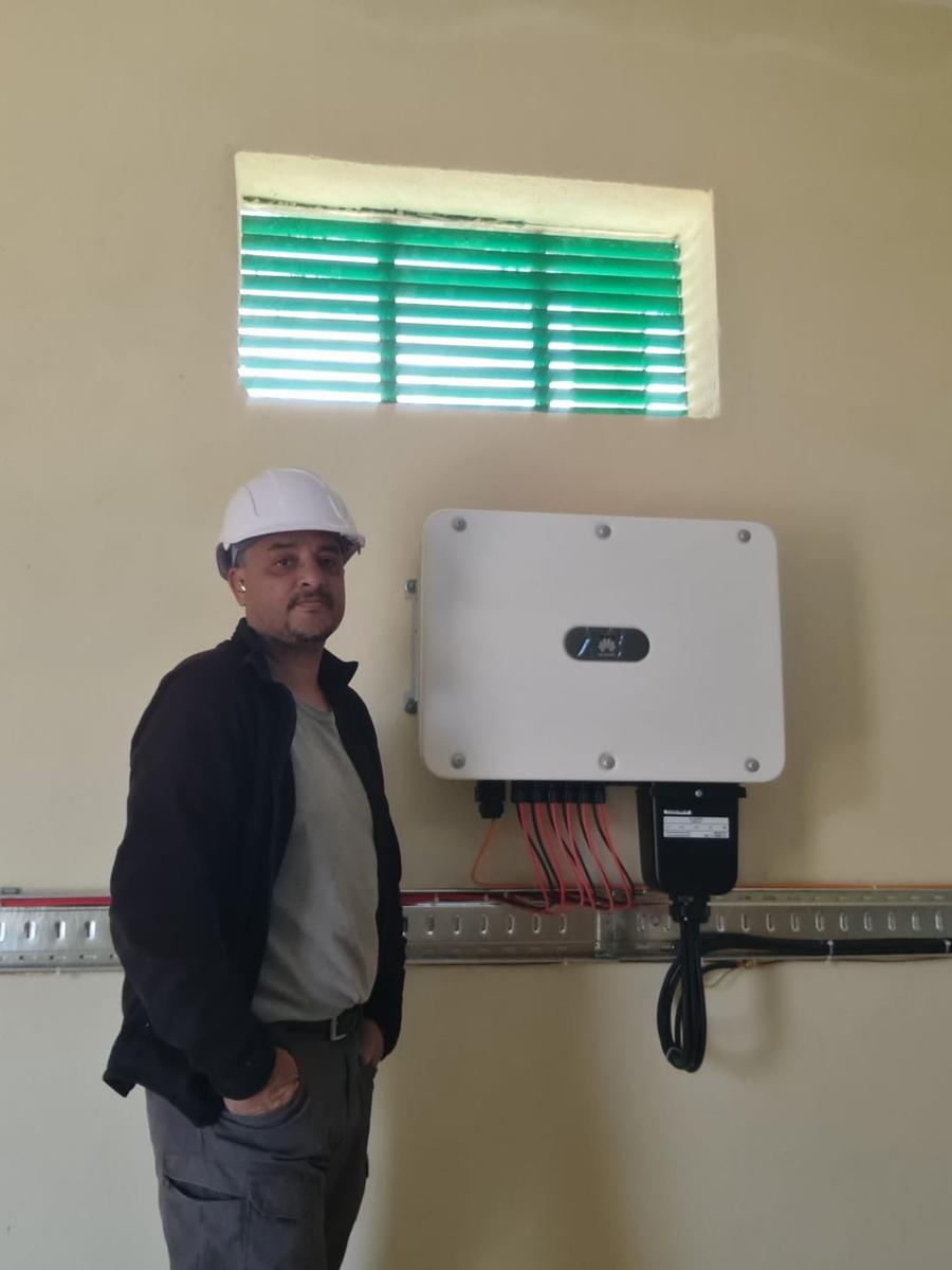 Technicien Sunenergy à côté d'un onduleur solaire